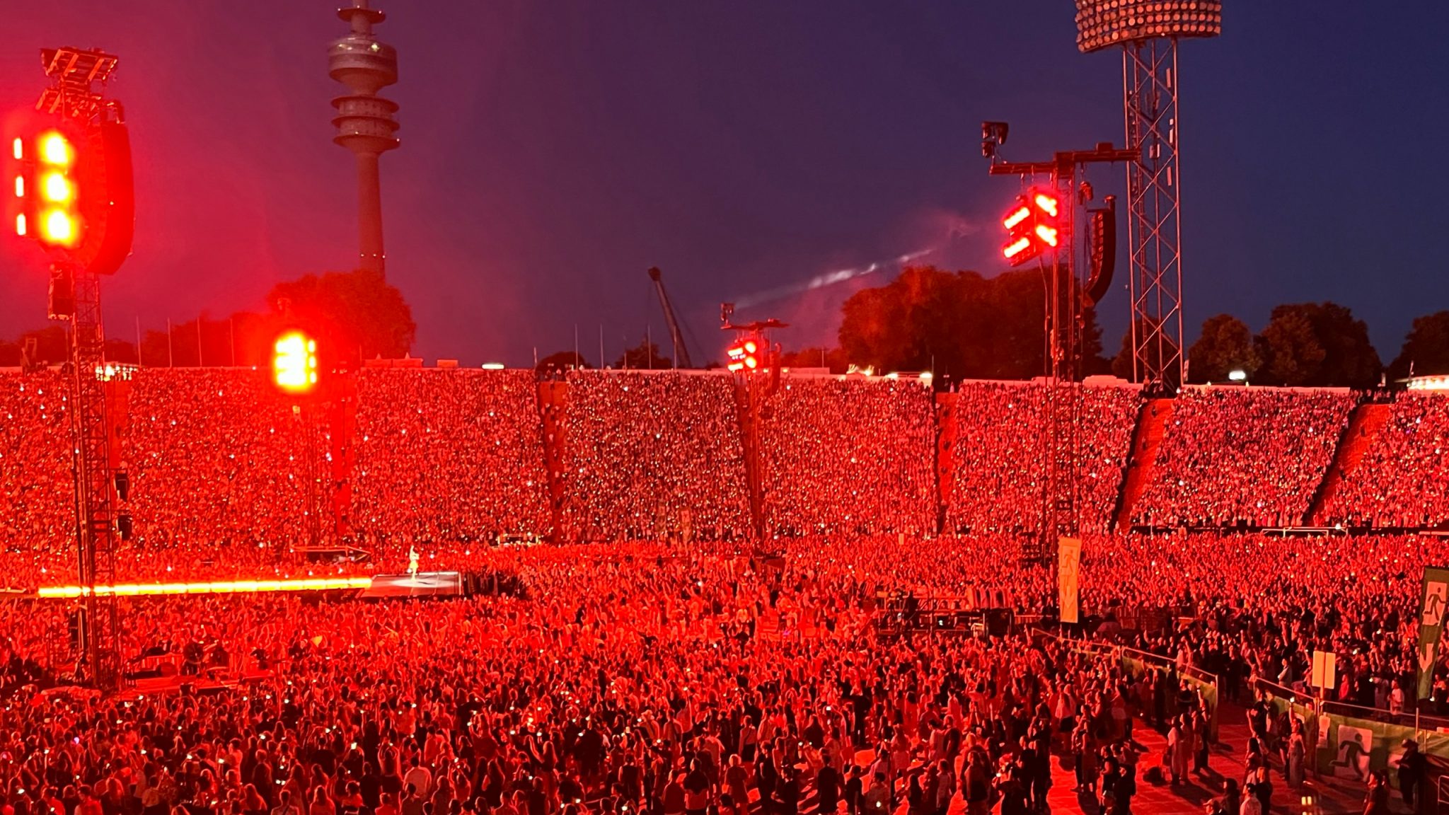 A sea of fans bathed in red light during a Taylor Swift concert, capturing the electric atmosphere of the night